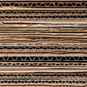 Close-up stack of corrugated cardboard sheets showing the wavy inner layers.