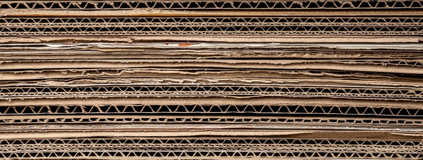 Close-up stack of corrugated cardboard sheets showing the wavy inner layers.